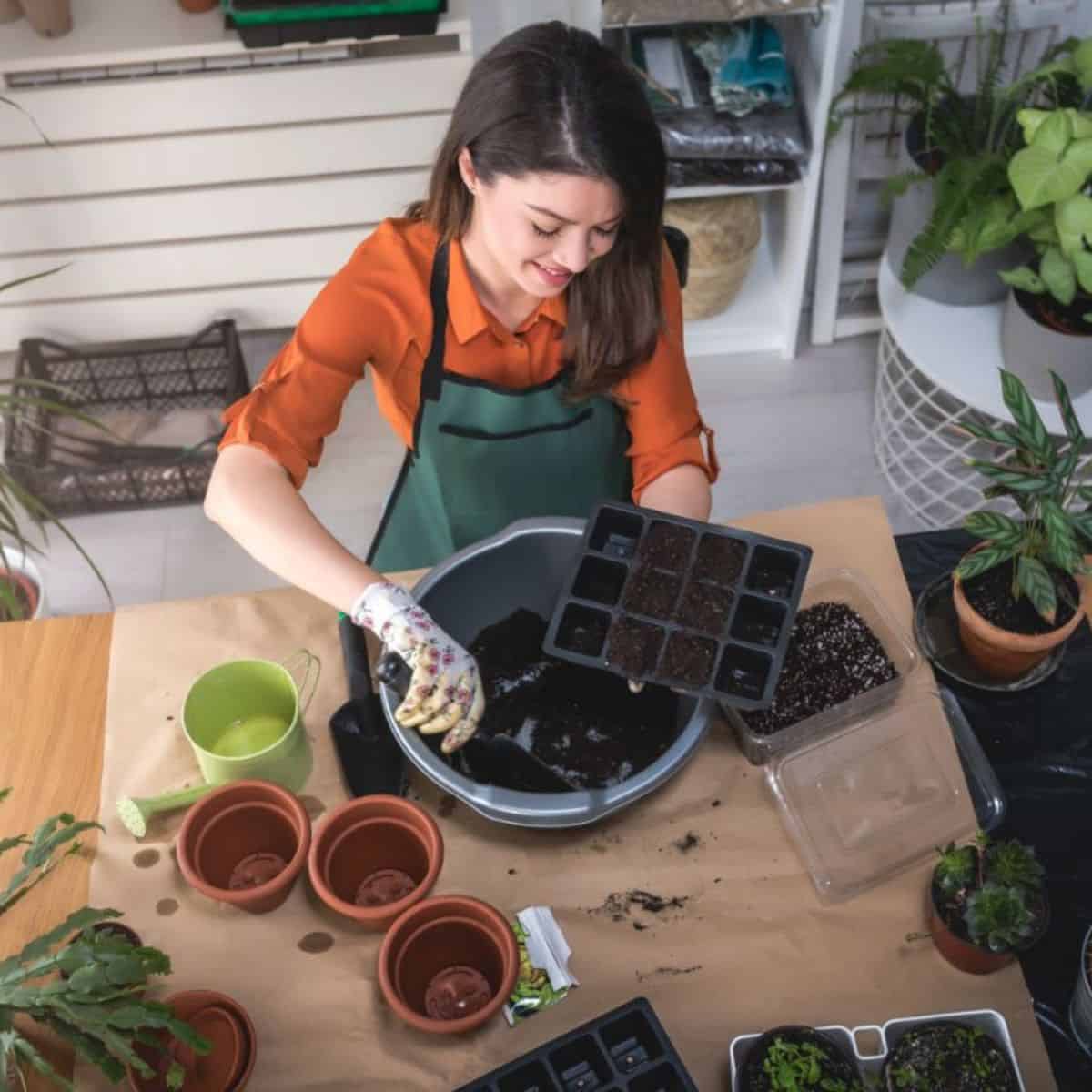 Happy-looking woman planting seeds into a big pot.
