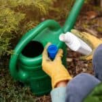 Woman pouring a liquid fertilizer on a field