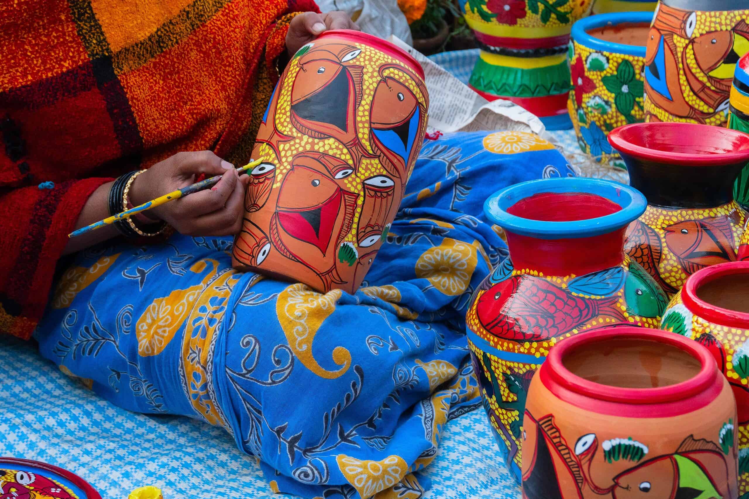 Female artist pianting terracotta pots.