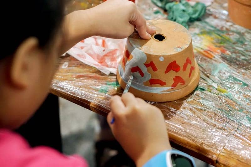 Female painting a terracotta pot.
